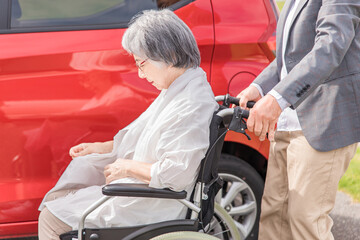 Wall Mural - 自動車の前で車椅子に乗った高齢者女性と男性
