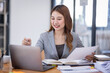 © David - Young asian business woman manager accounting analyst checking bills, analyzing sales statistics management, taxes financial data documents or marketing report papers working in office using laptop.