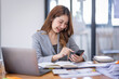 © David - Smiling young Asian business woman executive looking at smartphone using cellphone mobile cell tech, happy ethnic professional female worker working in office typing on cellphone sitting at desk.