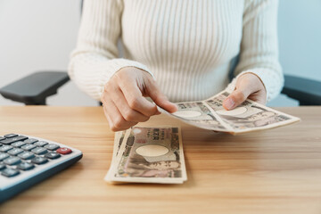 Poster - Woman hand counting Japanese Yen banknote with calculator. Thousand Yen money. Japan cash, Tax, Recession Economy, Inflation, Investment, finance, savings, salary and payment concepts