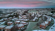 Freezing Cold Winter Cinematic Aerial View Of A Delicate Pink And Blue Early Morning Sunrise Sky. Urban Scene With Snow Covered Rooftops.