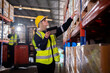 © APchanel - Worker industry warehouse in helmets woman order details and checking goods and supplies on shelves with goods background in warehouse is industry logistic and business export concept.