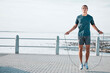 Skipping rope, mockup and man training by the beach for his outdoor morning exercise, workout and fitness routine. Athlete, cardio and male jump by the ocean or sea for wellness lifestyle