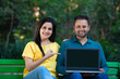 © PRASANNAPIX - Young indian couple showing laptop screen at park.