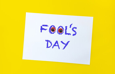 Text word Fool's day on sheet of paper with funny eyes and. 1 april message handwritting on sheet of paper. Bright yellow background. International humor day