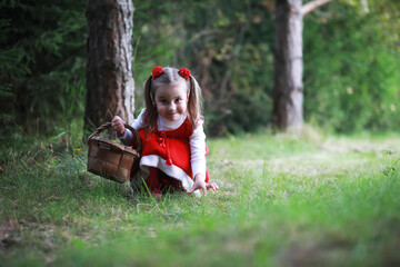 Wall Mural - A little girl in a red hat and dresses is walking in the park. Cosplay for the fairytale hero 