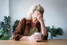 Depressed Senior Woman With Mug On Table At Home