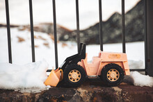 Toy Snowplow By Snow Near Fence In Winter