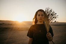 Young Woman With Dried Plants In Front Of Clear Sky At Sunset