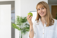 Happy Woman With Green Apple Standing At Home