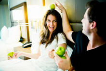 A Young Couple Sits In A Dallas Hotel Room Side By Side And Plays With Apples