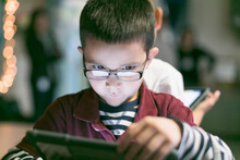 A Little Boy With Glasses Draws A Digital Art On His Tablet