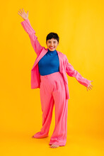 Happy Young Woman With Hand Raised Standing Against Colored Background