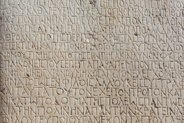 Historical inscription. Fragment of ancient greek text, carved on marble block at the archaeological site of Ephesus. Selcuk, Turkey (Turkiye). Ancient art and history concept. Retro background