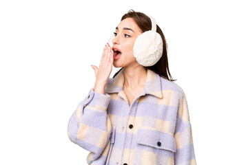 Wall Mural - Young caucasian woman wearing winter muffs over isolated chroma key background yawning and covering wide open mouth with hand