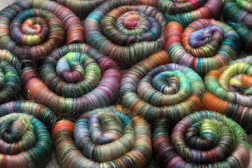 Closeup detail of handmade rolags of sheep wool and other fibres which were blended on a blending board ready for spinning on a  handspindle or a traditional spinning wheel.