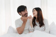 © itchaznong - Beautiful asian couple in love and smiling sitting on bed. Romantic moment, relationships, family concept.