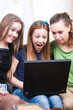 © danmorgan12 - Modern Lifestyle. Three Young Positive Laughing Caucasian Girlfriends Having Fun With Personal Laptop Computer Indoors.