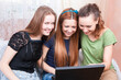© danmorgan12 - Modern Youth Lifestyle. Three Positive Young Happy Laughing Caucasian Girlfriends With Personal Laptop Computer Indoors.