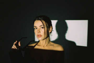 Canvas Print - Portrait of a fashion model with sunglasses posing in the studio. Film photography, noise and selective focus