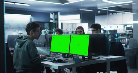 Diverse Software Development Department Working in a Cyber Security Artificial Intelligence Company. Web Engineer Working on a Computer with Two Green Screen Mock Up Displays. Footage from the Back
