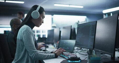 Fototapete - Portrait of a Thoughtful Young Engineer Working on Computer in a Technological Office Environment. Beautiful Asian Woman Wearing Headphones, Writing Software Code for a Blockchain Project