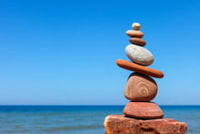 Rock Zen Pyramid Of Stones Of Different Shapes On A Background Of Blue Sky And Sea.