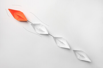 Wall Mural - Group of paper boats following orange one on white background, flat lay. Leadership concept