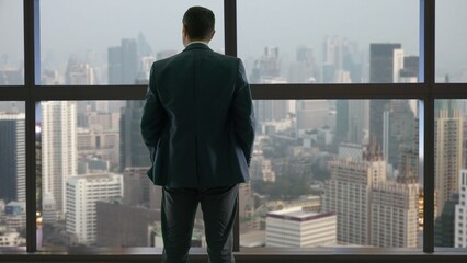 Man with hands in the pocket look out window and admire sky scraper view, power