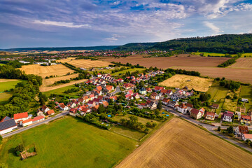 Aer ial view of a German village surrounded by meadows, farmland and forest in Germany.