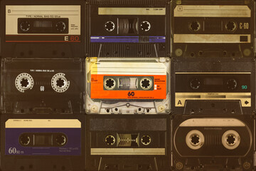 Wall Mural - one vintage colorful orange compact cassette in front of black audio tapes