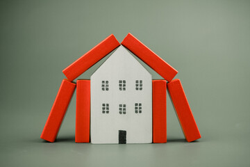 Poster - Home protection concept. Red wood block sheltering house. Real estate, housing and mortgage crisis, foster home care