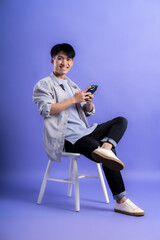 Canvas Print - full body image of young asian man using phone on purple background