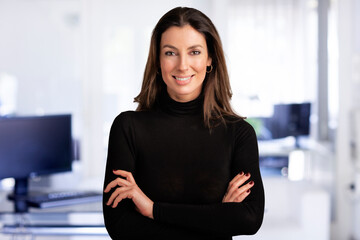 Wall Mural - Confident businesswoman wearing turtleneck sweater and smiling while standing at the office