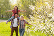 © Angelov - Happy parents mom and dad, daughter, young family outdoors in spring against the background of blooming apple and cherry trees