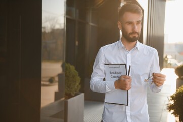 Businessman or real estate agent ready to discuss business and stands against new building