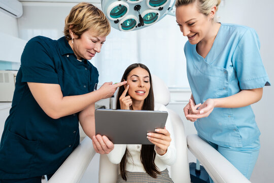 beautiful and happy brunette woman at beauty medical clinic. she is sitting and talking with two fem