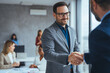 © Dragana Gordic - Portrait of cheerful young manager handshake with new employee. Business partnership meeting in office. Close up of handshake in the office. Mature businessman shake hands with a younger colleague