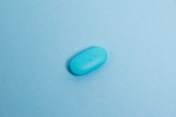 Wall Mural - Vitamins in pills on blue paper background, medical capsule close-up