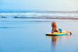 Little baby girl - young surfer with bodyboard has fun on sea beach. Family lifestyle, people outdoor water sport lessons and swimming activity on summer vacation with child in adventure surf camp.