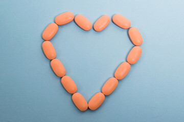 Wall Mural - Pink pills laid out on a paper background in the shape of a heart, flatlay. Concept of prevention and treatment of heart diseases