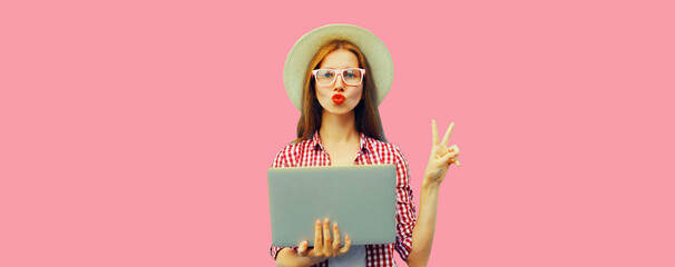 Portrait of modern cool young woman with laptop on pink background