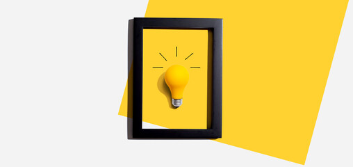 Wall Mural - Yellow light bulb inside a frame - inspiration, creativity, energy, electricity themes