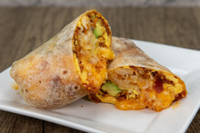 Overhead View Of Chorizo Breakfast Burrito With Eggs, Salsa, And Cheese All Wrapped In A Grilled Flour Tortilla To Eat