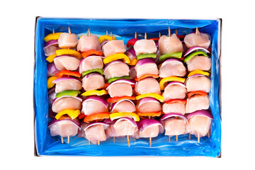 Wall Mural - RSkewers with pieces of raw meat, red, yellow and green pepper.aw chicken skewers with vegetables, peppers,plums,onions, in a cardboard box on a white background. Close-up.Top view.