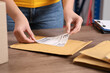 Post office worker sticking barcode on parcel at counter indoors, closeup