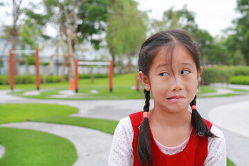 Portrait of young Asian girl kid make a sassy and cheeky face in the garden.