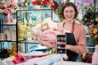© tigercat_lpg - E-commerce business, one young White female florist demonstrates and shows floral arrangements via online live streaming with smartphone application in bright flower shop, beautiful blossoms store.