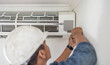 © Lumeez/peopleimages.com - Air conditioner, ac repair and maintenance of a handyman and builder working on home renovation. Electric technician, service worker and contractor in a house for equipment installation on wall