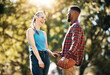 © Allistair F/peopleimages.com - Couple, American football in park and happy together, summer with hand holding outdoor and sports in the sun. Commitment, trust and fitness, black man and woman, interracial relationship and care